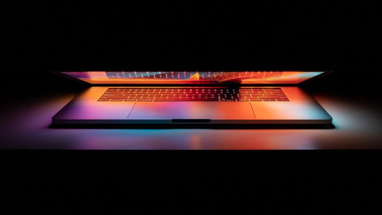 Partially open laptop showing orange glow in darkened room