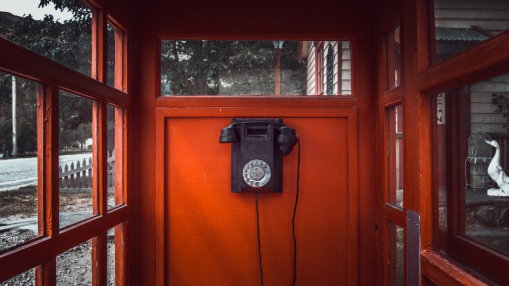 Black rotary dial phone in red booth