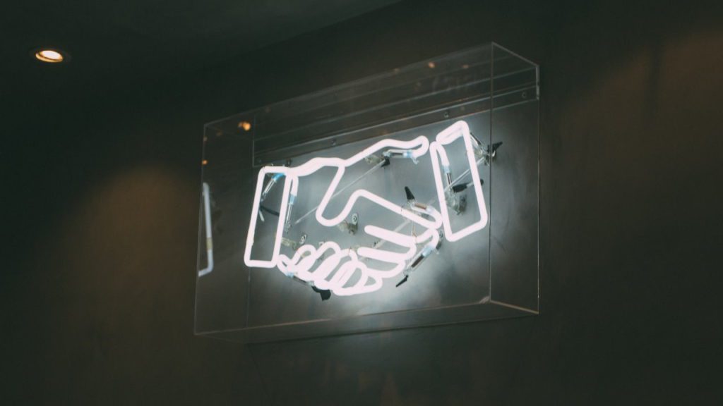 Neon sign of hand shake